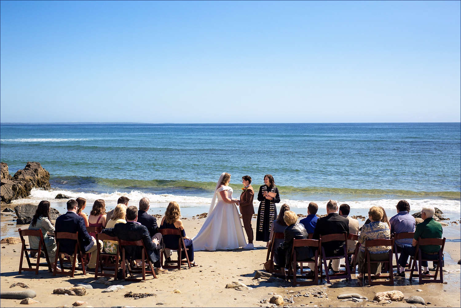 The family and friends watch the brides get married on the beach of Marginal Way Maine