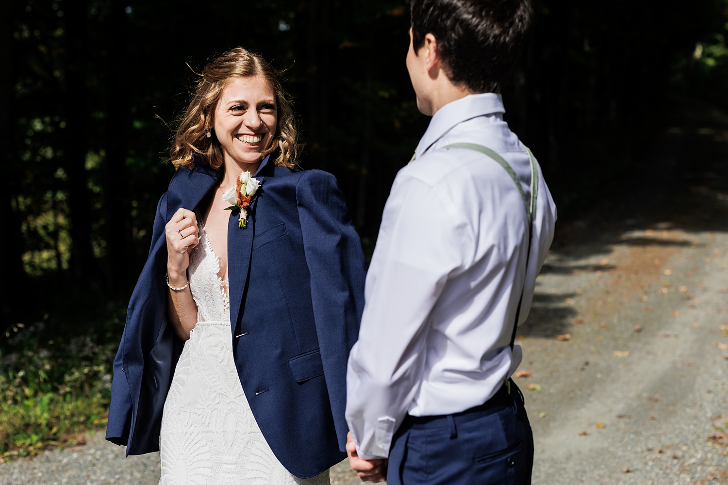 The bride smiles in her groom's suit coat