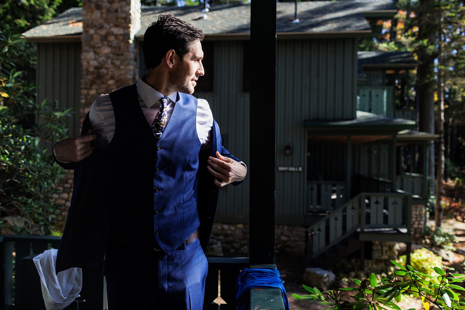 The groom gets ready on the porch of his cabin on his wedding day