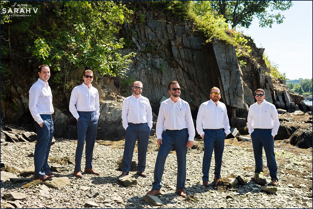 The groomsmen all pose on the rocky shore of Portsmouth NH