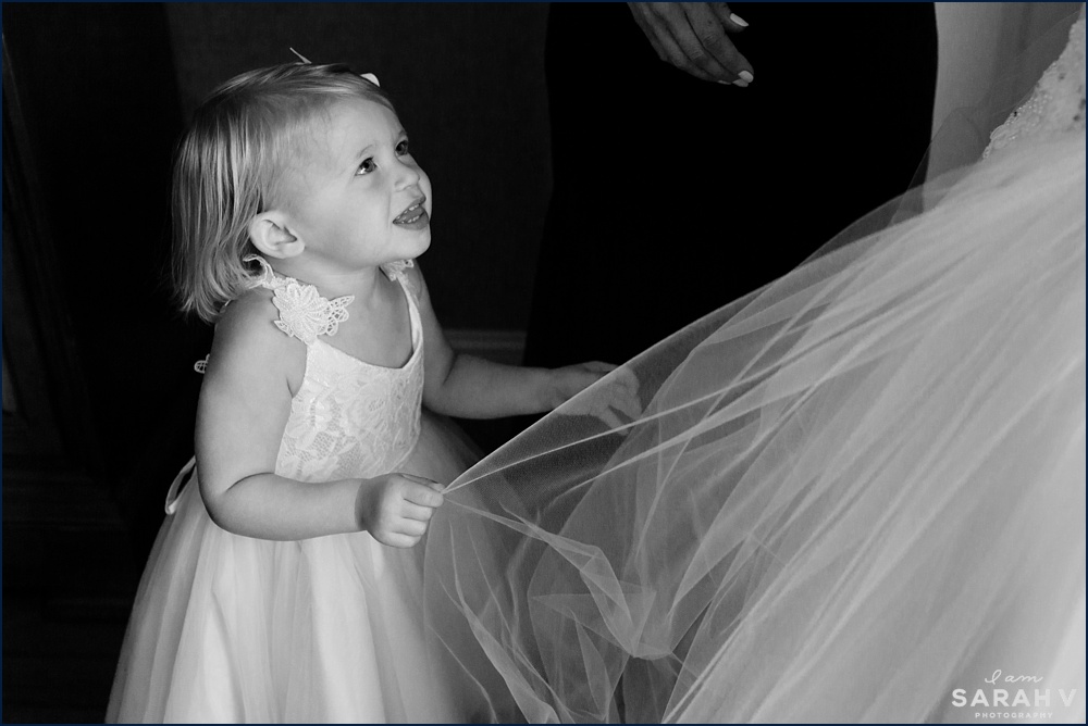 The flower girl plays with the bride's wedding dress tulle