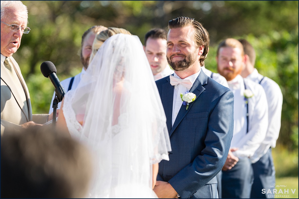 The groom smiles lovingly at the bride during their oceanfront wedding ceremony