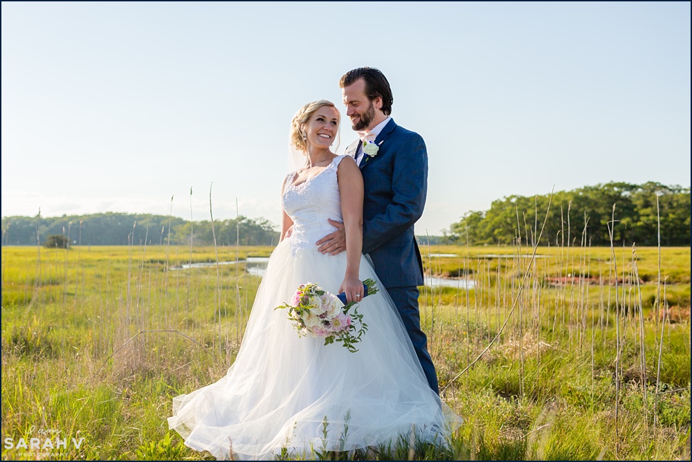 The bride and groom stand by the marsh along the ocean shore in Rye New Hampshire