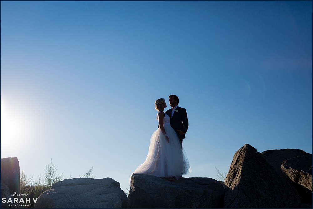 The bride and groom are silhouetted against the bright sky on their wedding day down by the water at Seacoast Science Center