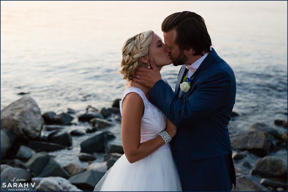 The bride and groom kiss on the ocean shore at the Seacoast Science Center