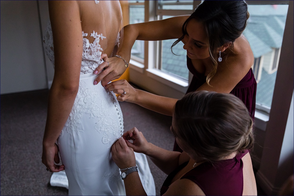 Waterville Valley New Hampshire Wedding bride gets some help getting into her lace filled wedding dress