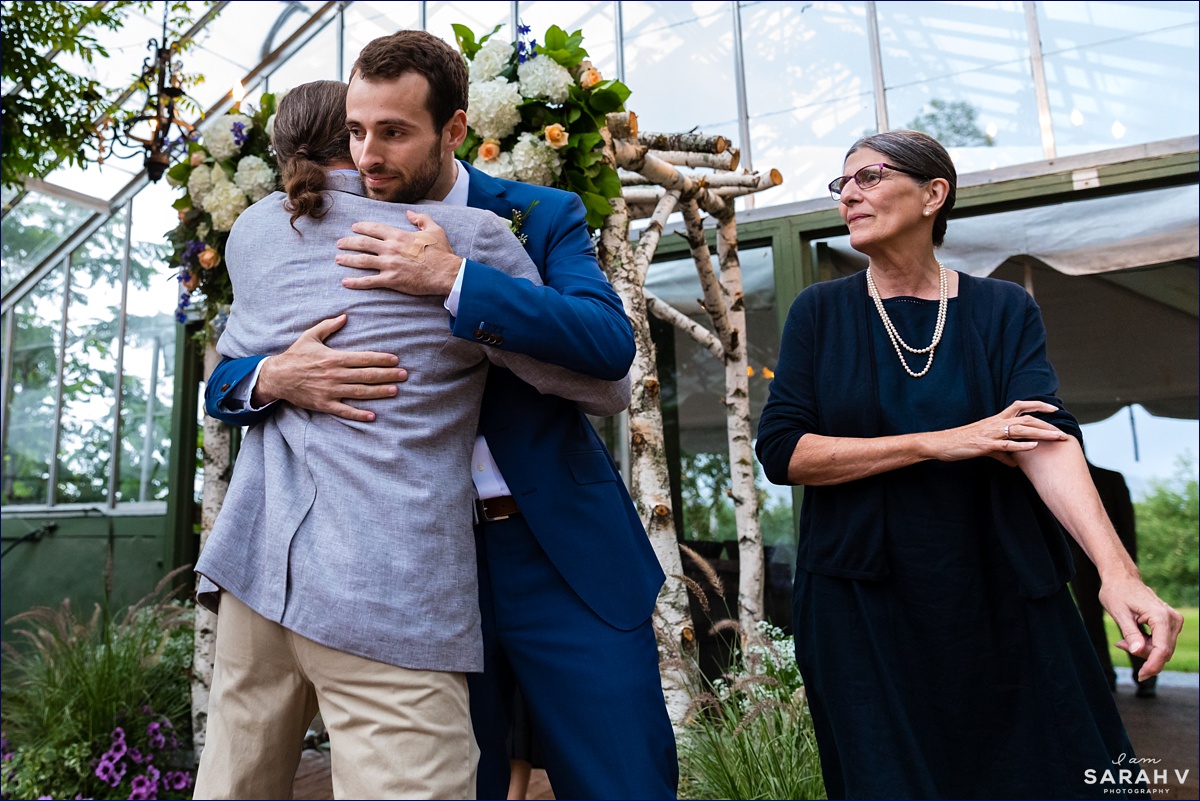 Common Man Italian Farmhouse wedding the groom hugs his parents during the intimate wedding ceremony in the greenhouse