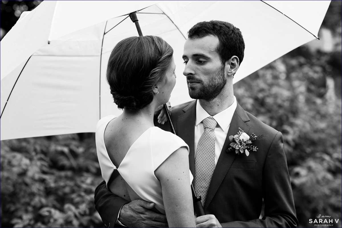 The groom looks at his bride under the umbrella after their outdoor wedding in New Hampshire