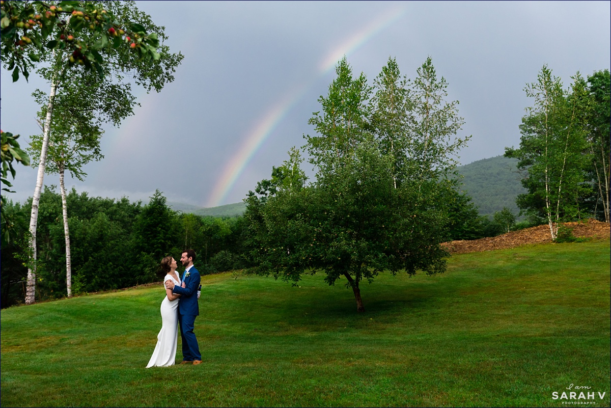 The bride and groom laugh in front of the rainbow after their intimate NH wedding on a rainy day