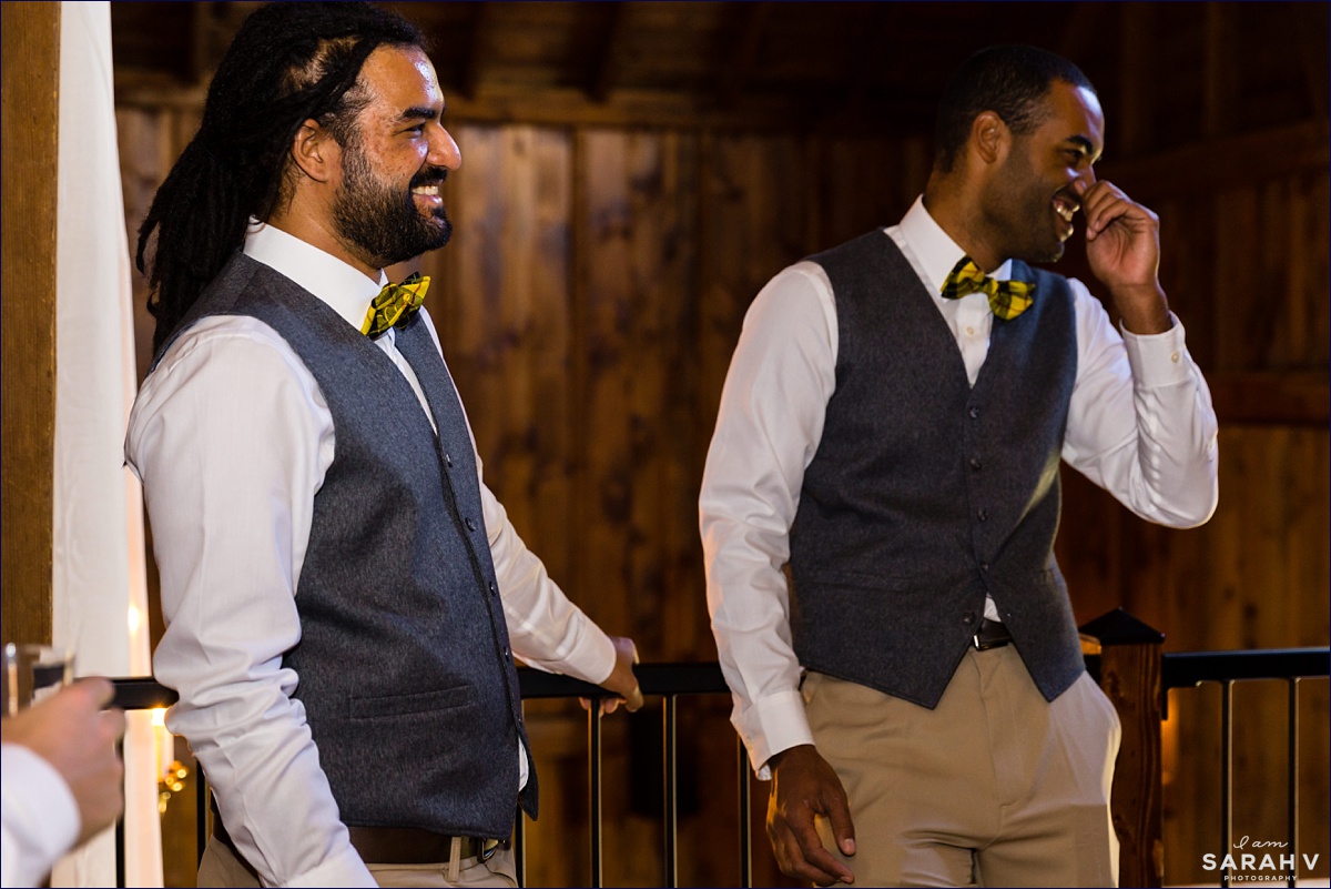 The groomsmen laugh while getting ready in the barn on the outdoor fall wedding day