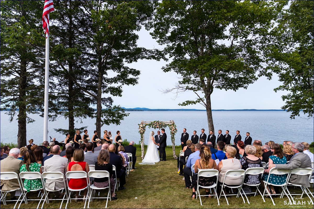 The wedding ceremony at the Pot and Kettle Club in Hulls Cove Maine with a beautiful water view and gardens as the backdrop