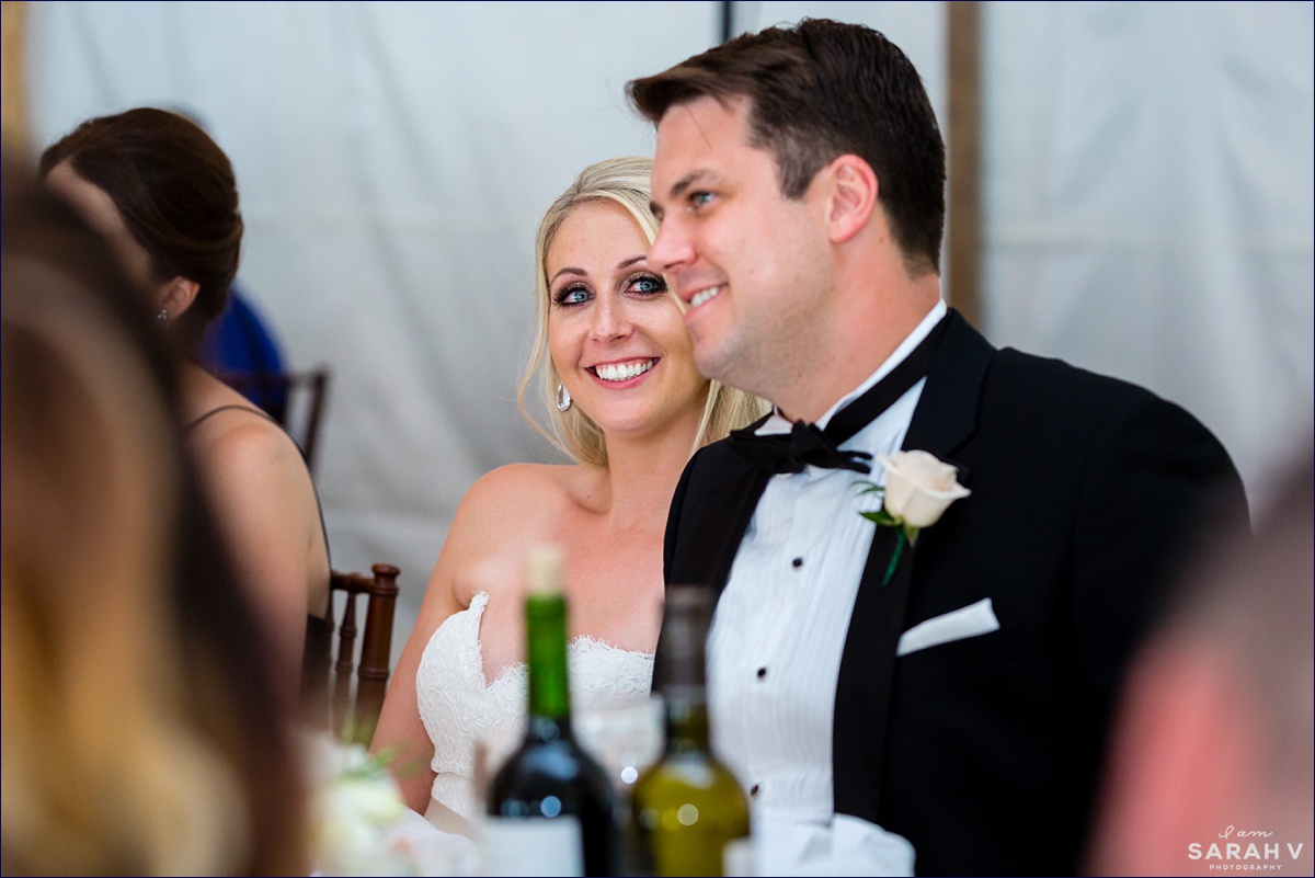 The bride smiles at her husband as they listen to toasts at their northern Maine wedding