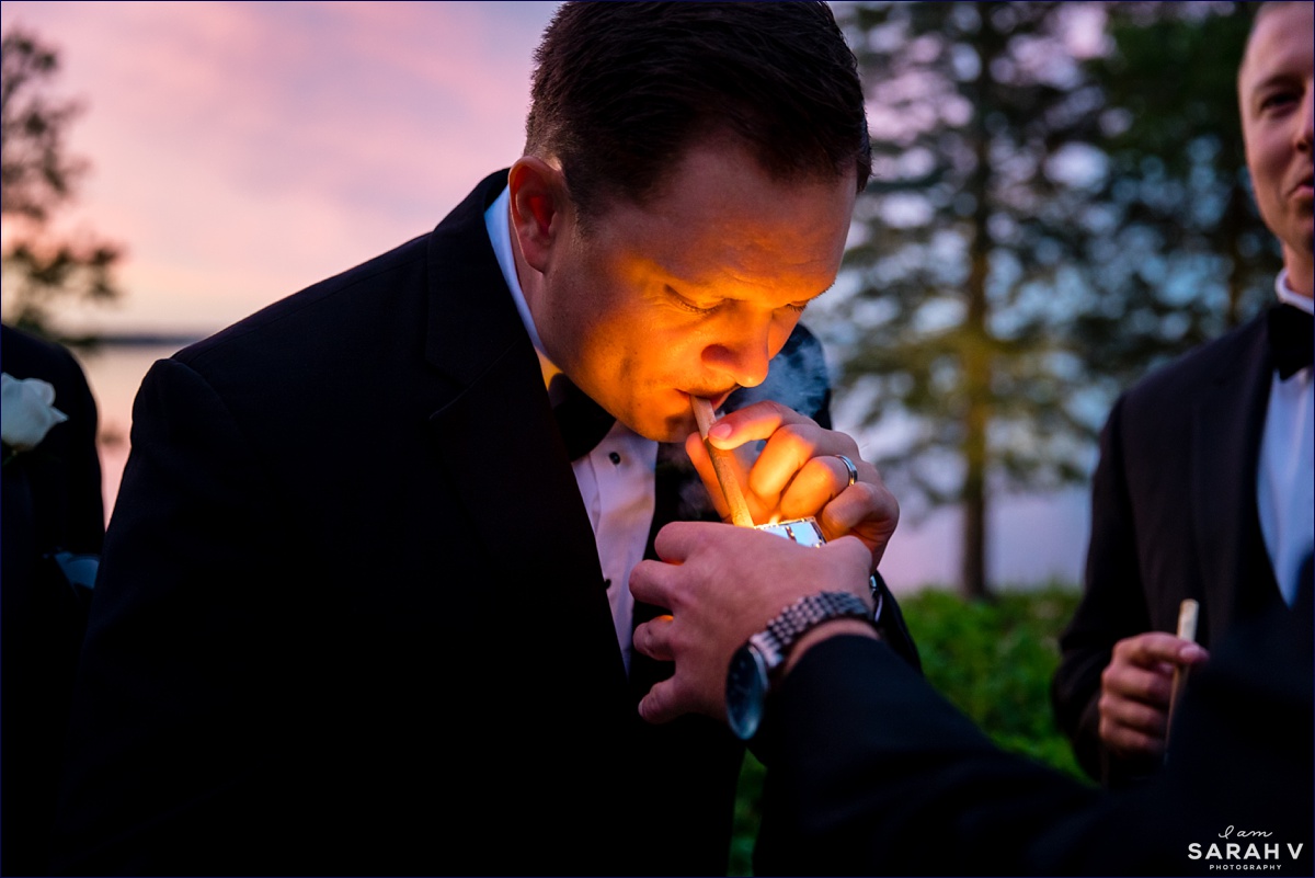 A groomsman lights a celebratory cigar at his friends wedding reception in Maine