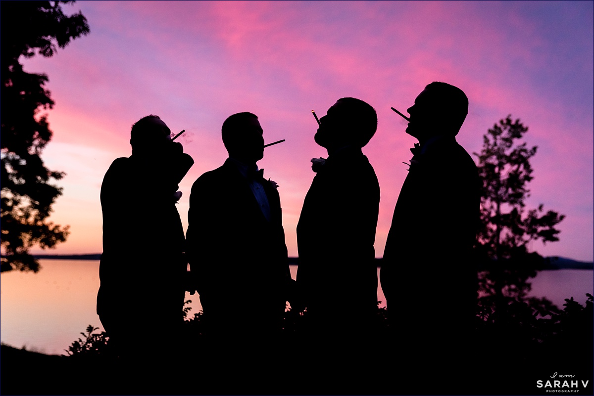 The groomsmen pose with their cigars in front of the sunset in Hulls Cove Maine