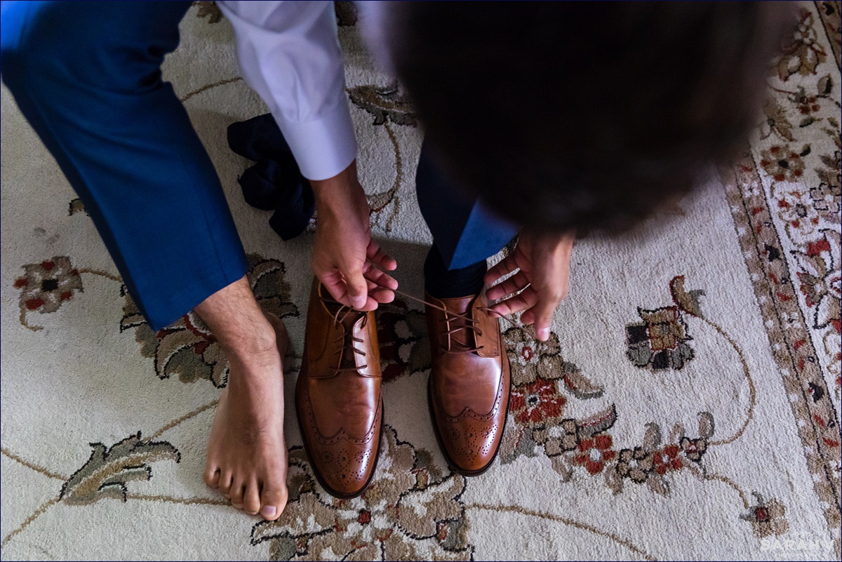 Groom ties his shoes at the Ivy Manor Inn before his wedding in Bar Harbor Maine