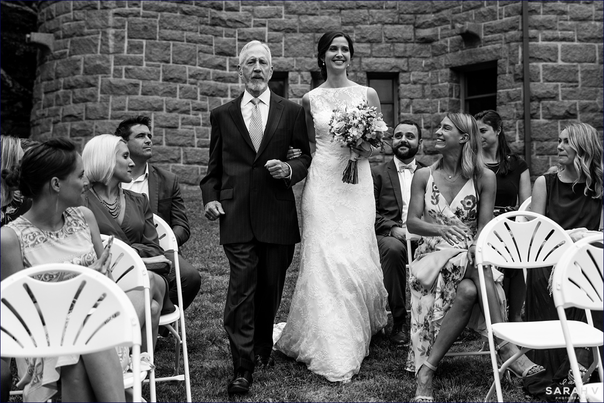 The bride enters the wedding ceremony at the College of the Atlantic in Bar Harbor Maine with her father on her arm at her intimate wedding