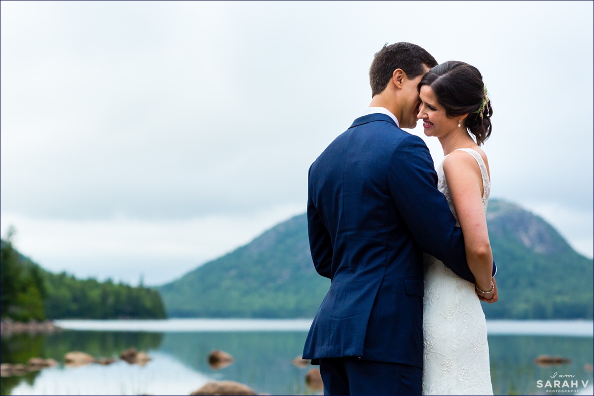 The groom gets in close with the bride and gets her to laugh as they stand on the shores of Jordan Pond on Mount Desert Island