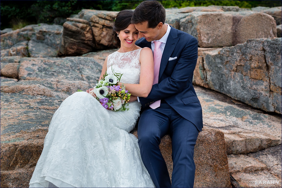 The bride and groom snuggle close together out on the cliffs of Acadia for their wedding day photos