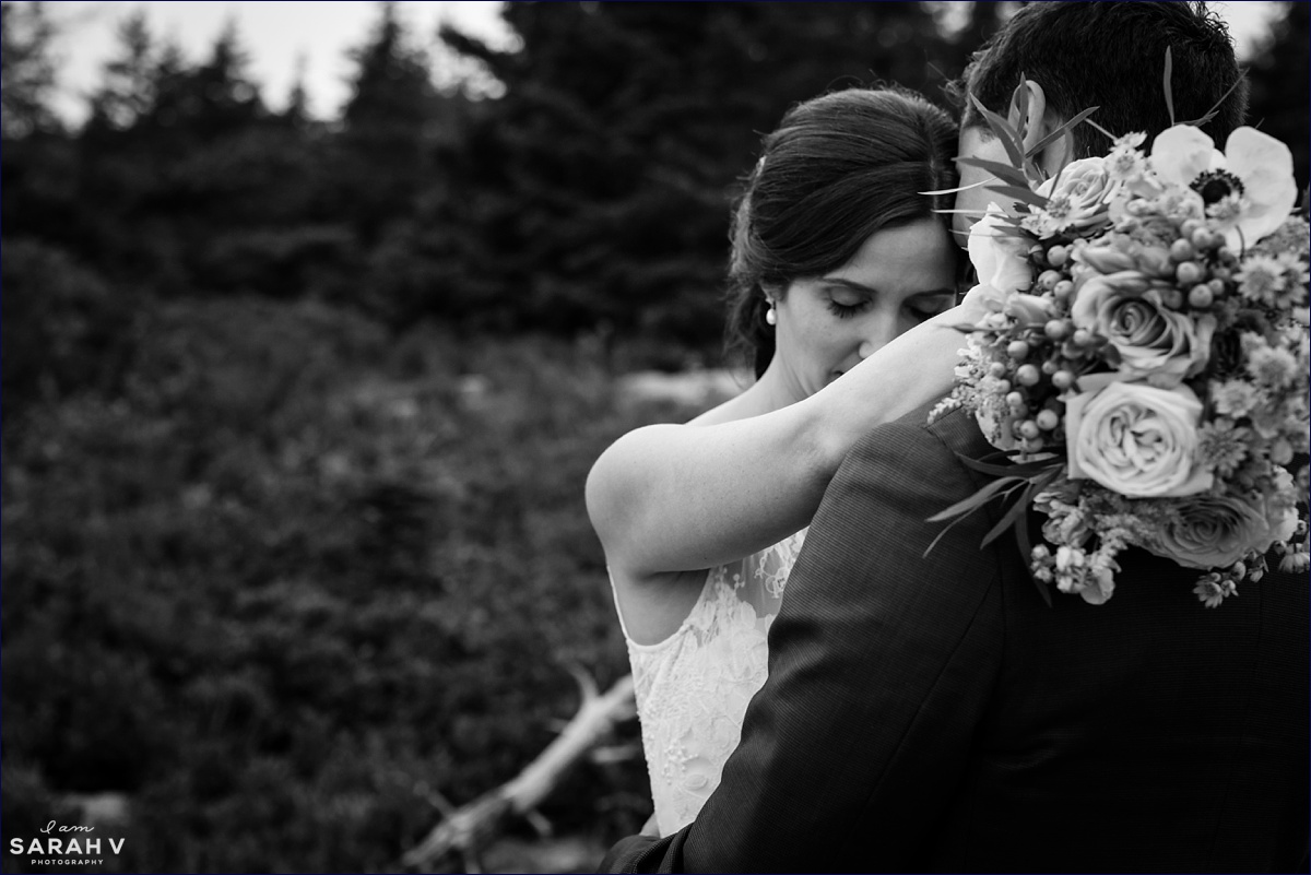 The bride hugs the groom while they take photos on their wedding day in Acadia National Park