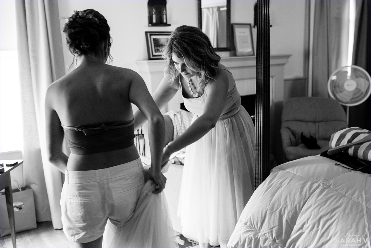 A bridesmaid helps the bride get into her wedding gown before they head to the ceremony