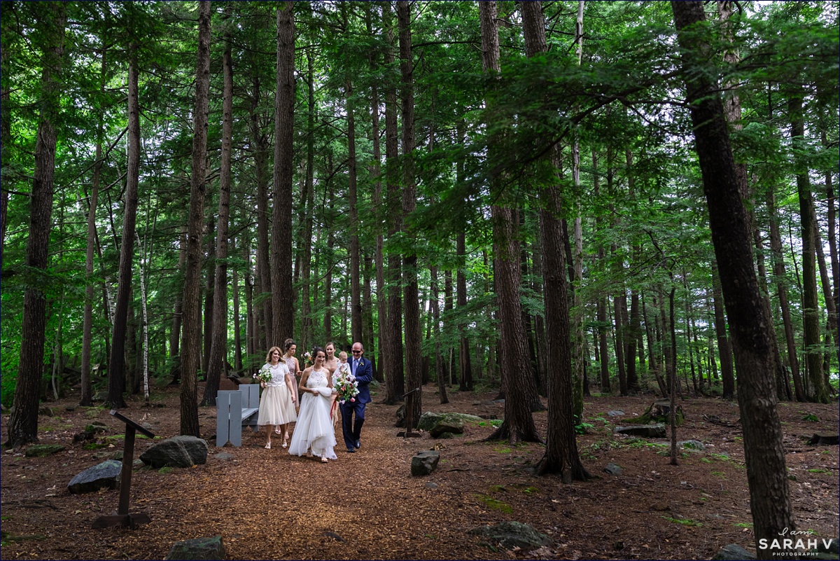 Church Island wedding ceremony in New Hampshire, the bride and her wedding party walk the wooded path to the outdoor chapel on the island before the ceremony starts
