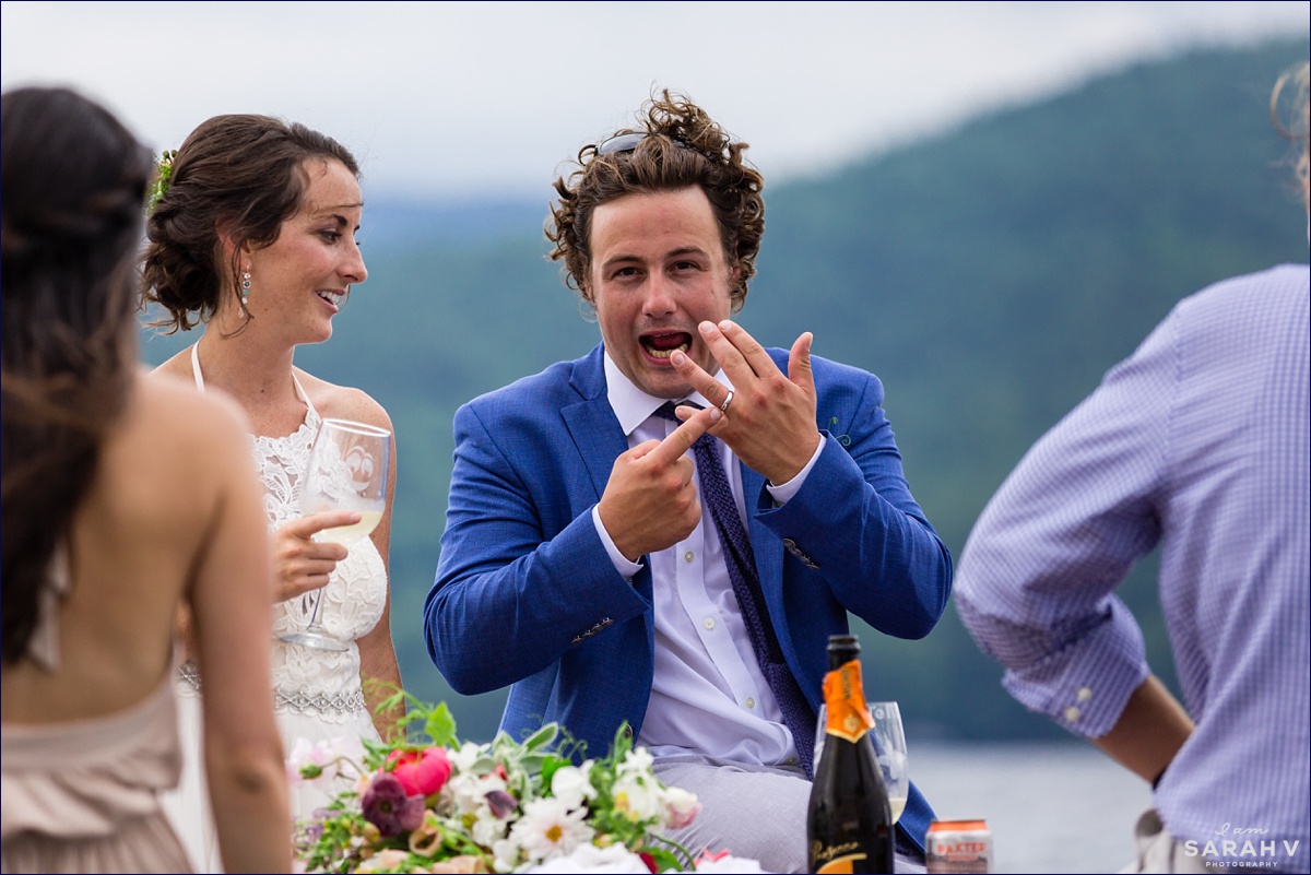 The groom points to his brand new wedding band on his finger while riding a boat back to shore in NH