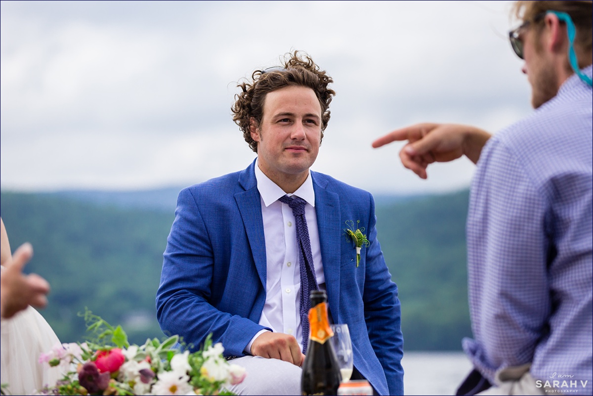 The groom talks with his friends on the boat on Squam Lake NH on their wedding day