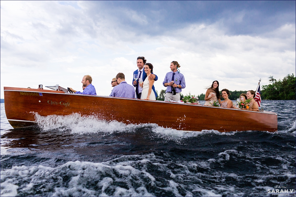 Squam Lake NH wedding photographer the wedding party all quickly dash across the water while toasting before the rain storm catches up with them in their Cris Craft boat