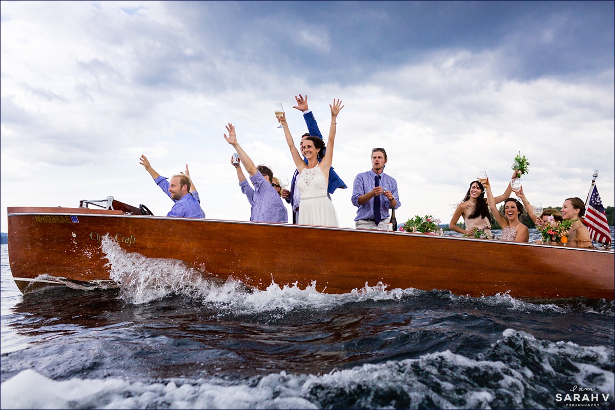 The wedding party all celebrate and wave to guests who are also racing across the water to the camp reception in New Hampshire