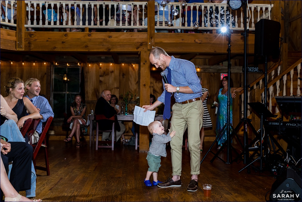 Inside the barn at The Preserve at Chocorua wedding the best man gives a toast while his son joins him for warm words to the newlyweds in Tamworth NH