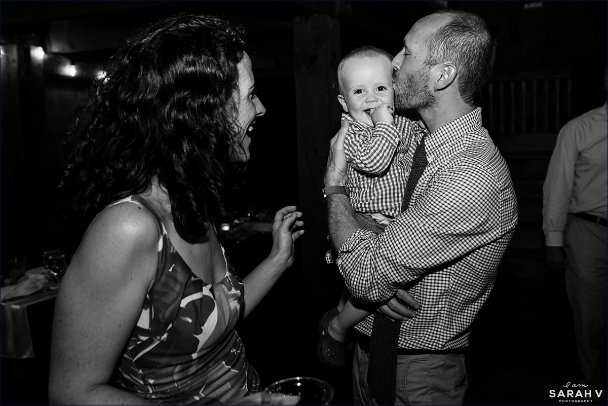 The best man shares a kiss with his young son on the dance floor with a guest at the couple's barn wedding