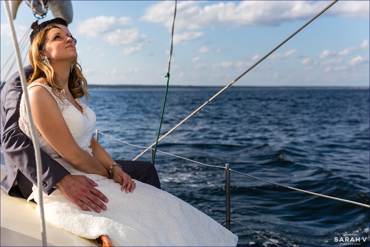 The bride looks up at the large sail on the Silverlining Sailboat out of Perkin's Cove Maine