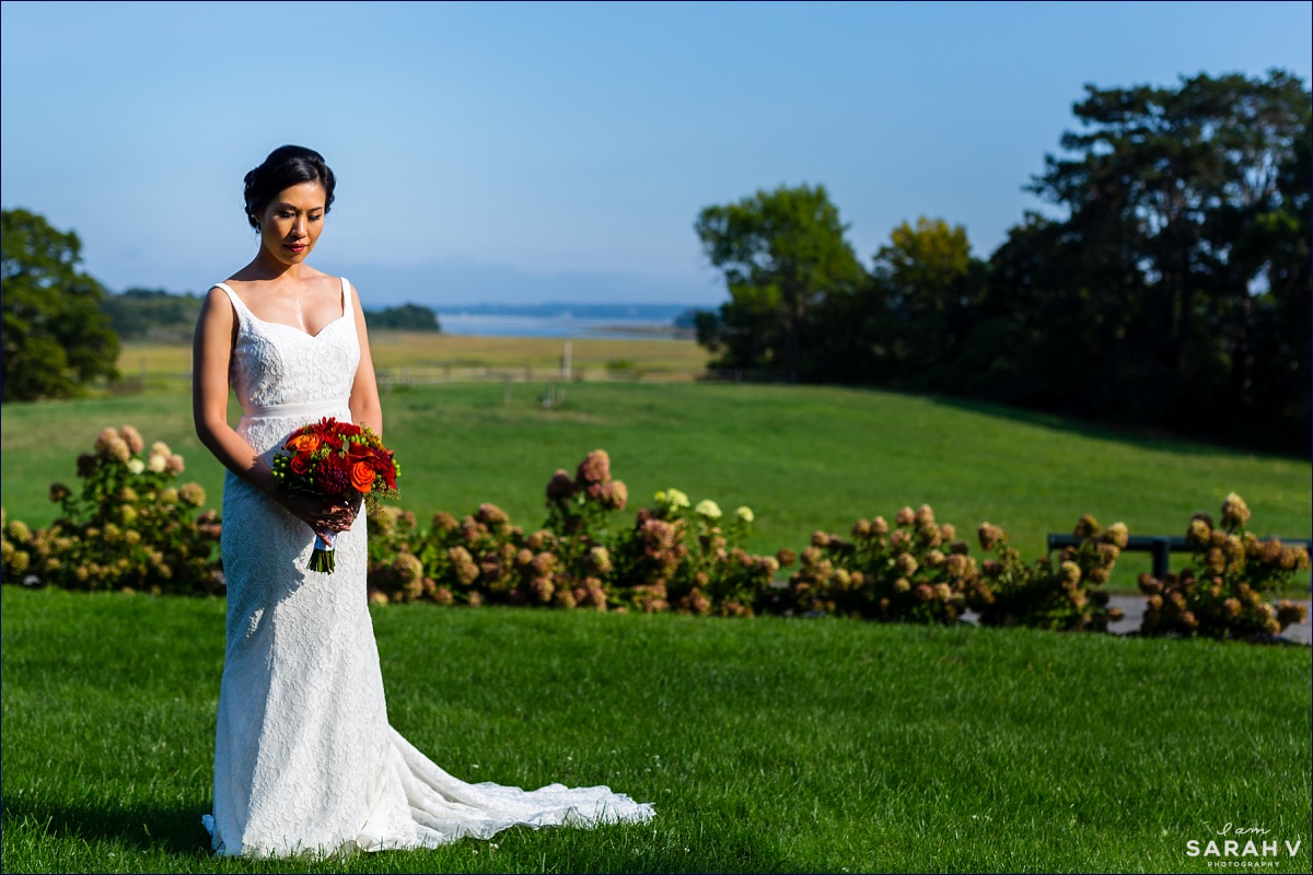 The bride stands on the grounds of Crane Estate and holds her fall inspired wedding flowers on a sunny day