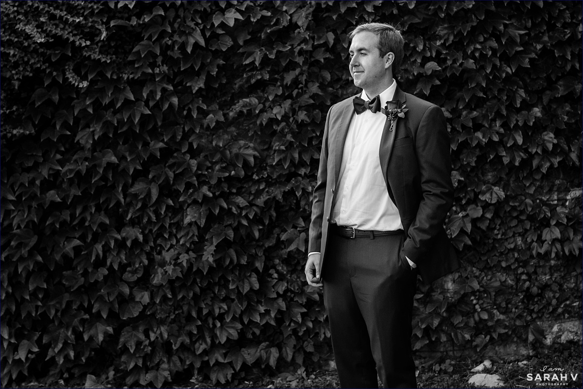 The groom gets a quick portrait in while standing in front of an ivy wall on the grounds of Crane Estate