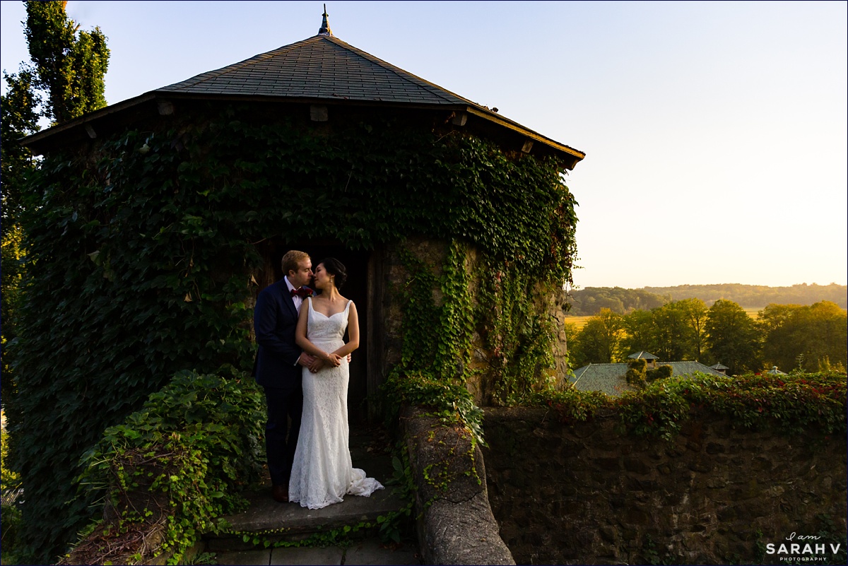 The Barn at Crane Estate wedding the bride and groom stand next to the stone pillars with ivy growing up them overlooking Ipswich on their wedding day