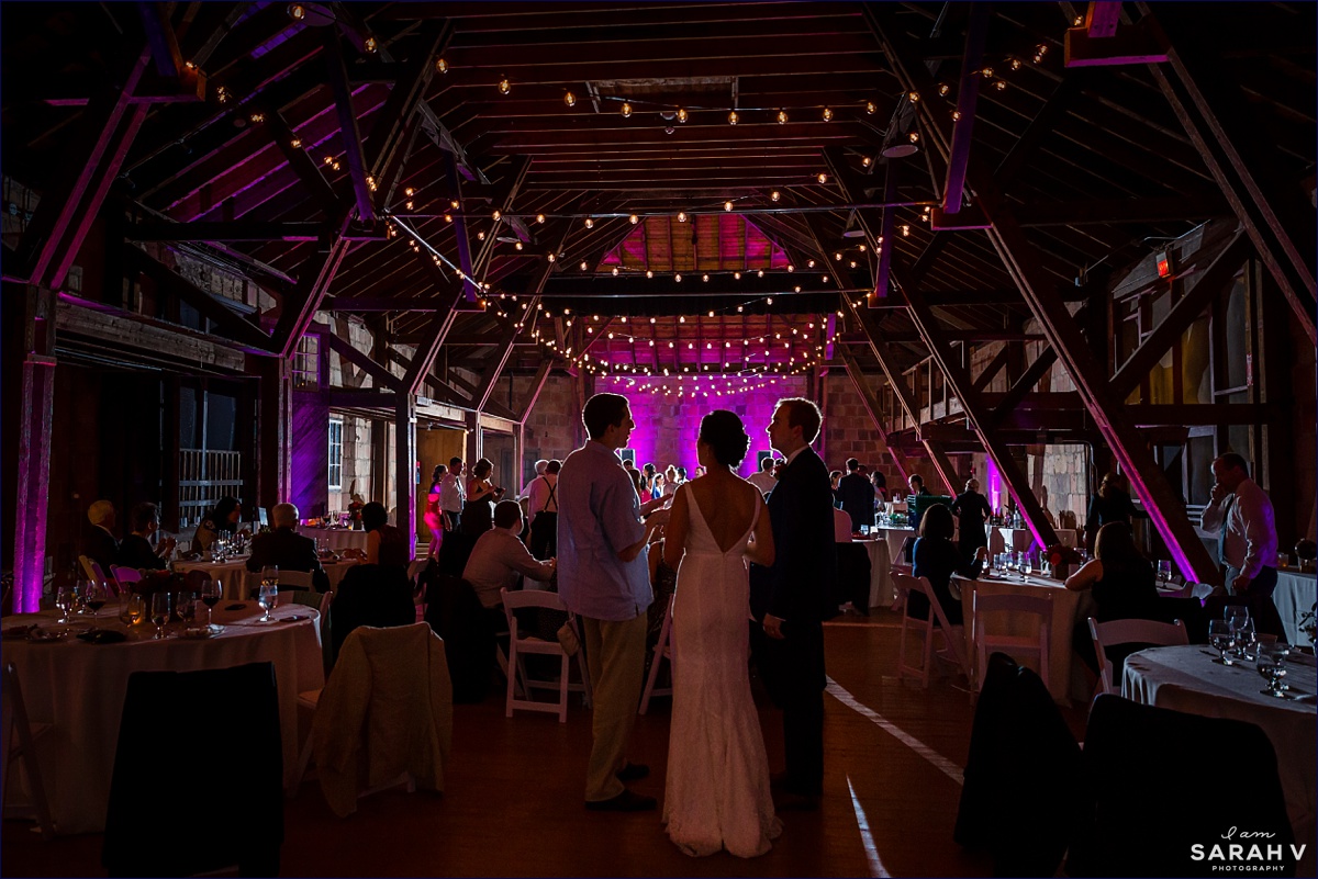 The Barn at Crane Estate wedding reception is in full swing as the newlyweds talk to guests and others dance