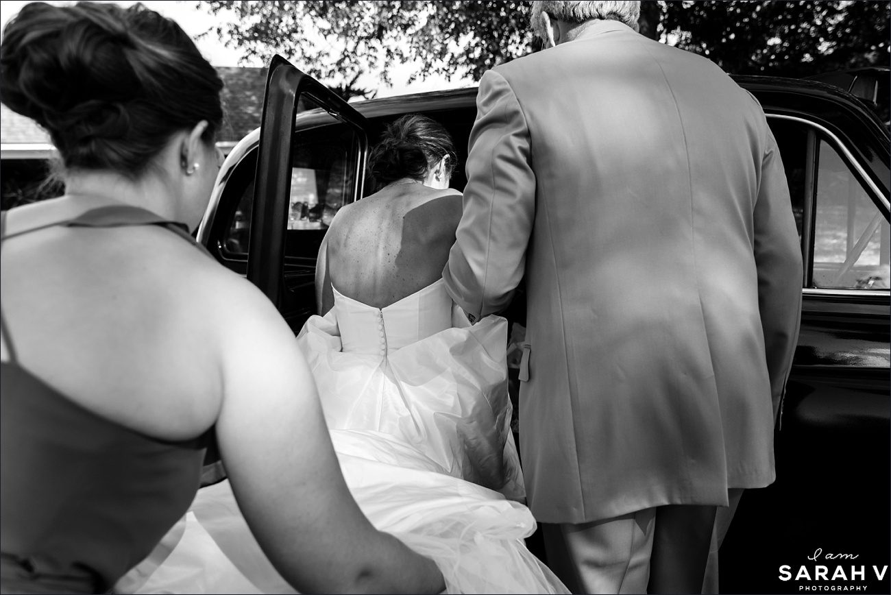 The bride gets into a vintage car with help from her dad and her maid of honor as they head to the ceremony in Dublin NH