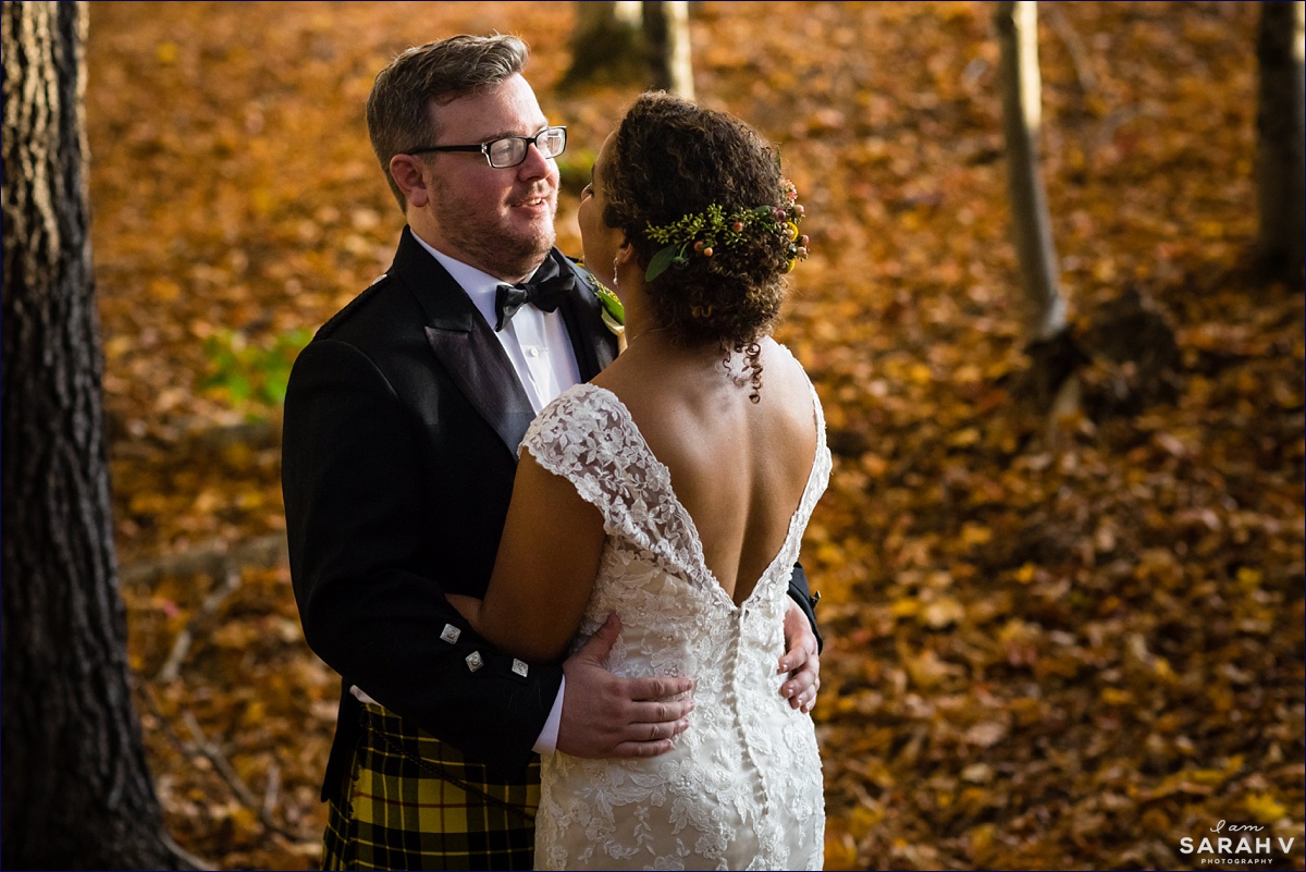 The groom smiles at his bride while they stand in the leaves on the farm's property