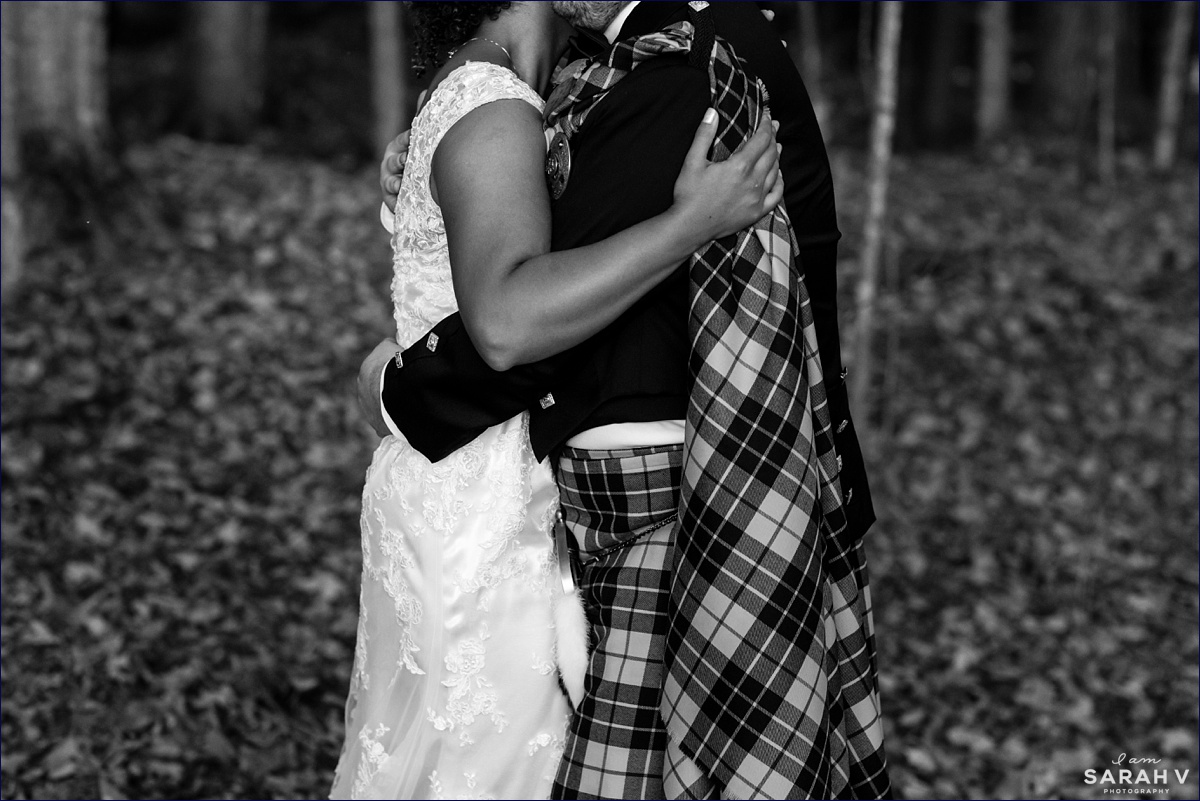 The bride and groom hold each other close while dancing among the leaves at the Maine farm wedding while he is in a custom kilt