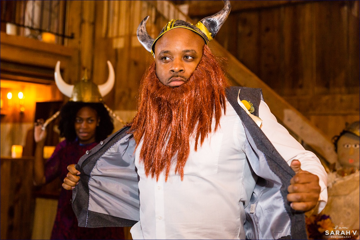 Groomsman dances with a viking helmet and a beard at the Maine barn wedding reception