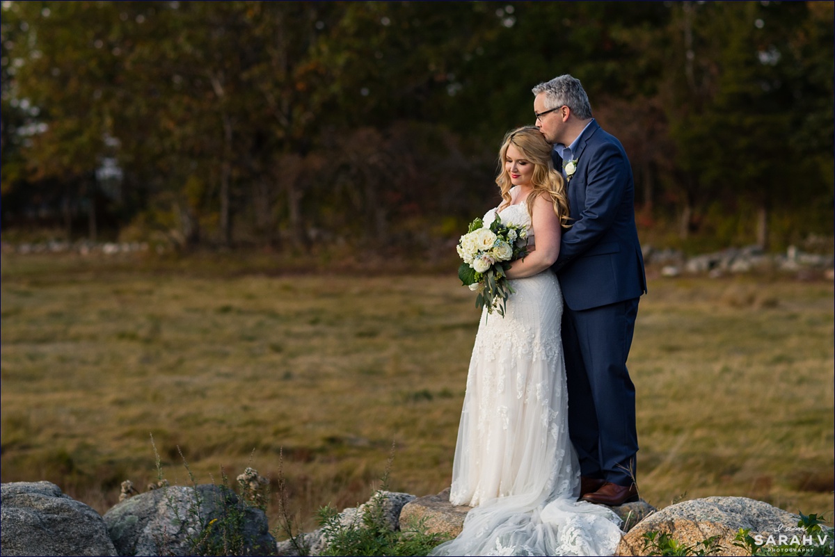 The bride and groom stand in front of the beach grass in Odiorne Point State Park in NH