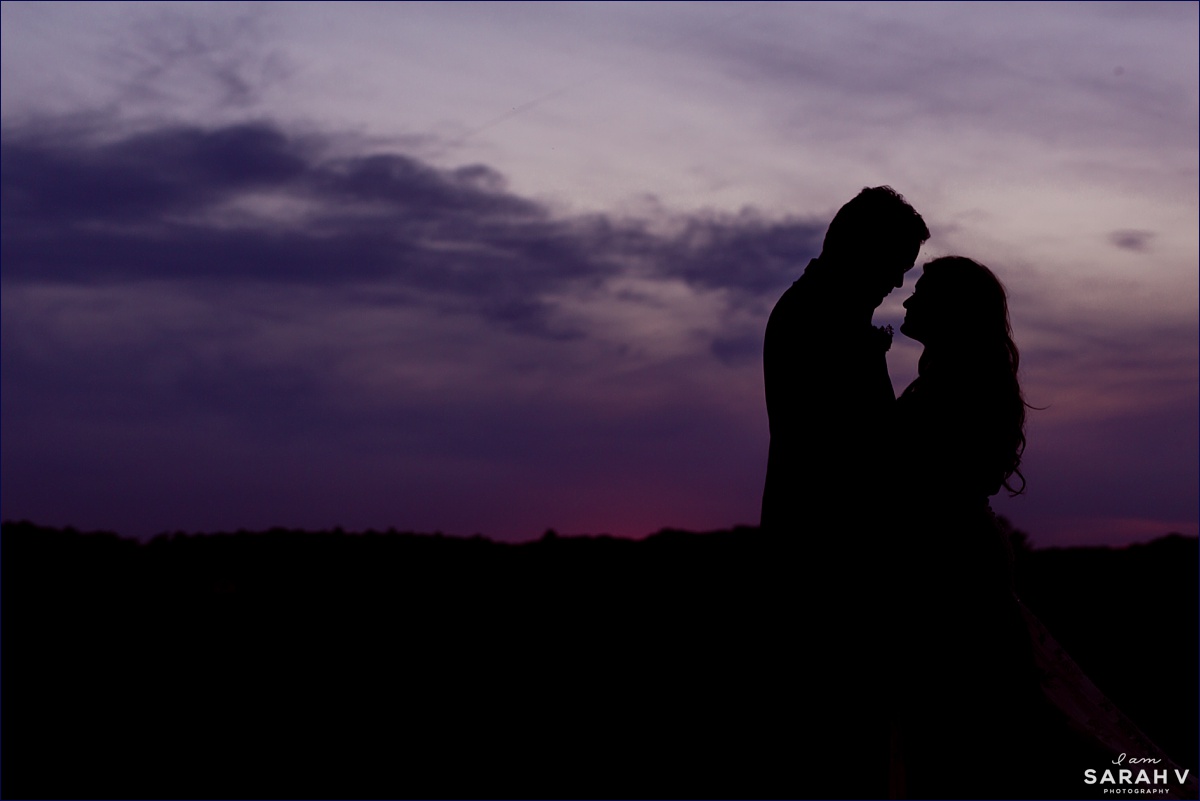 A silhouette of the newlyweds against a sunset sky on their New Hampshire wedding day