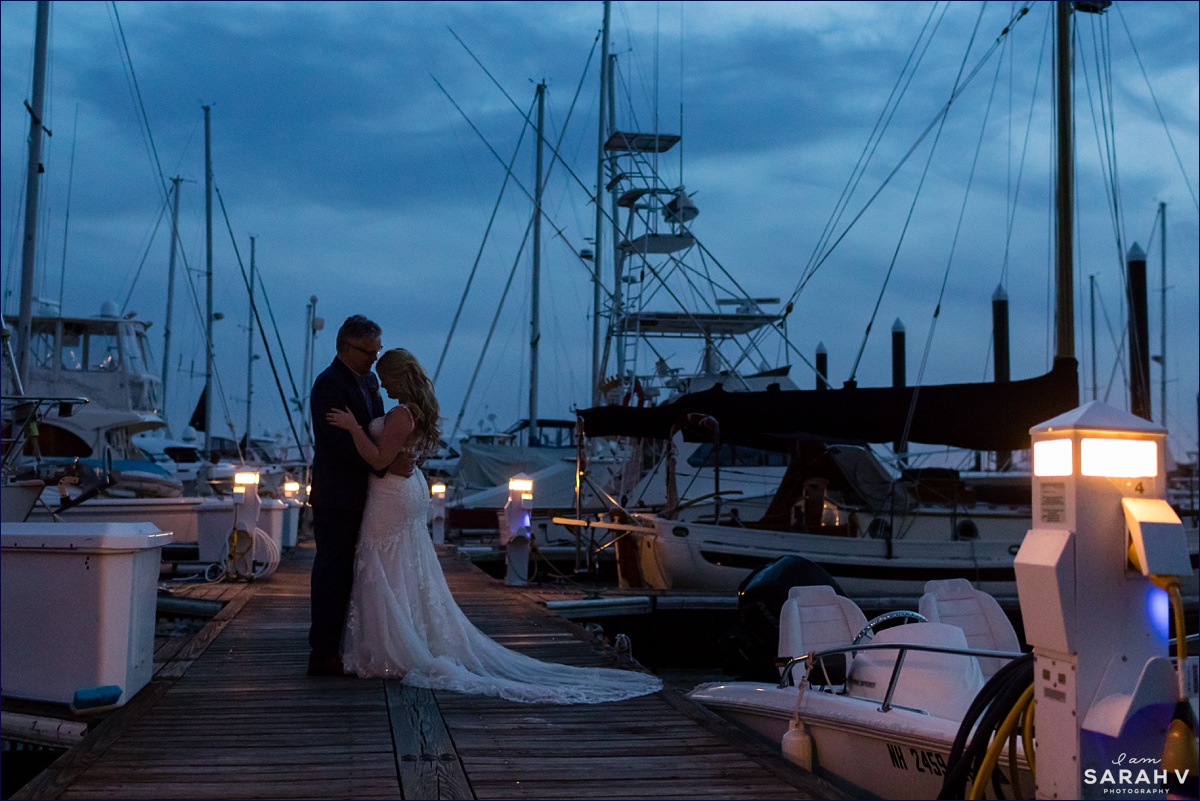 The bride and groom dance on the docks at Wentworth by the Sea with the boats and sailboats behind them as the sun disappears