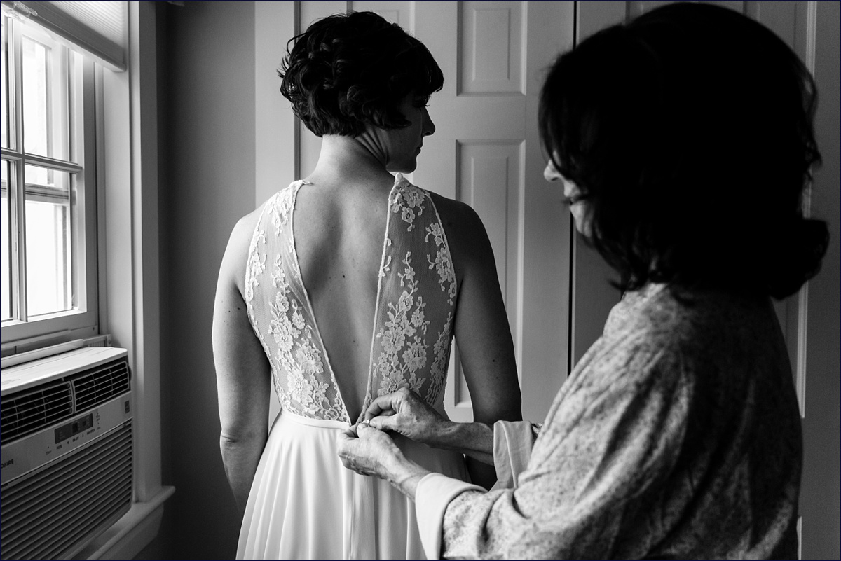 Bride gets into her wedding gown with the help of her mother