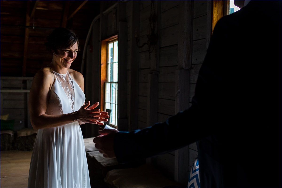 Bride marvels at her groom during their first look in the hay loft of the barn