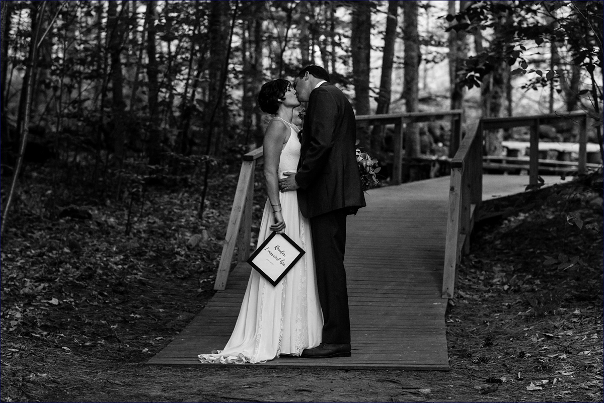 Hardy Farm bride and groom romantically kiss at the foot of the woods with a framed literature quote in hand