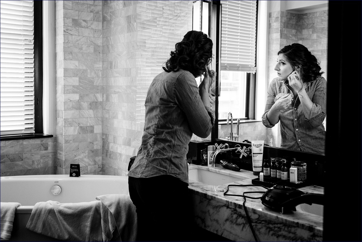 Portland Maine Wedding Photographer getting ready at the Press Hotel the bride puts on her earrings
