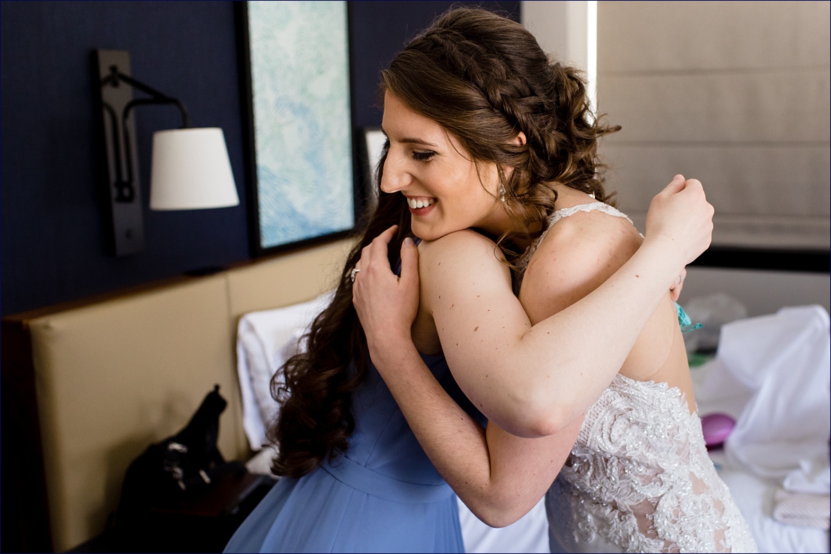 The bride hugs her maid of honor as they exchange gifts on her wedding day