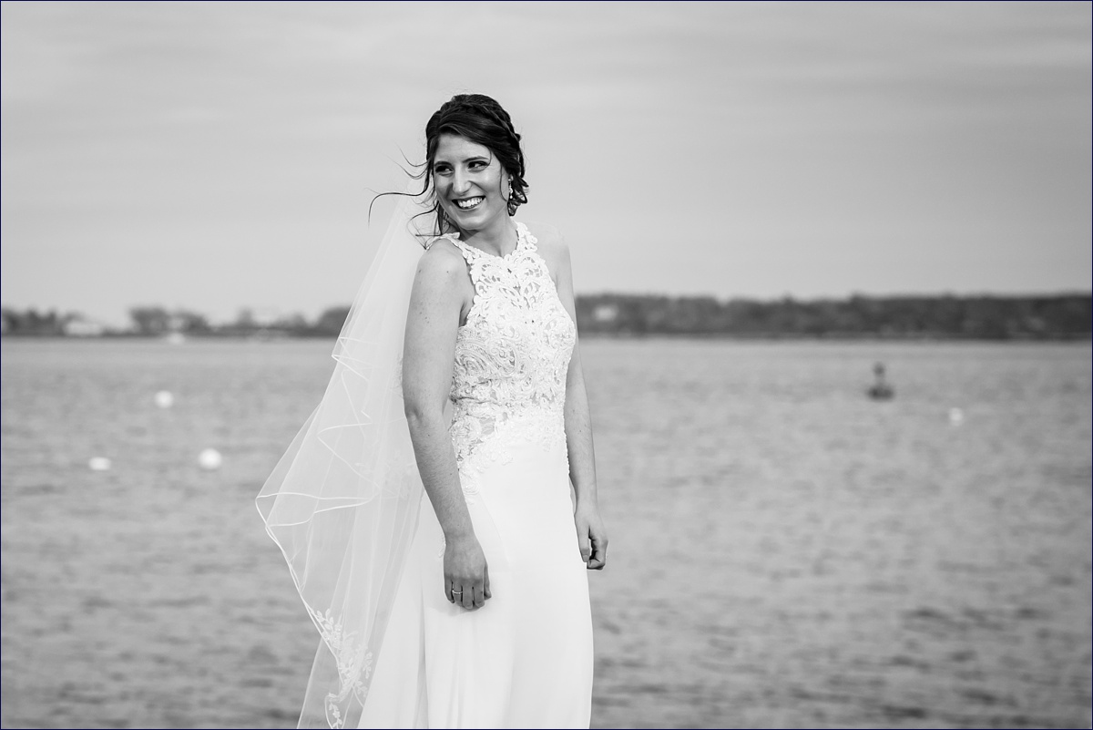 The bride smiles at her husband on the Eastern Promenade in front of the ocean