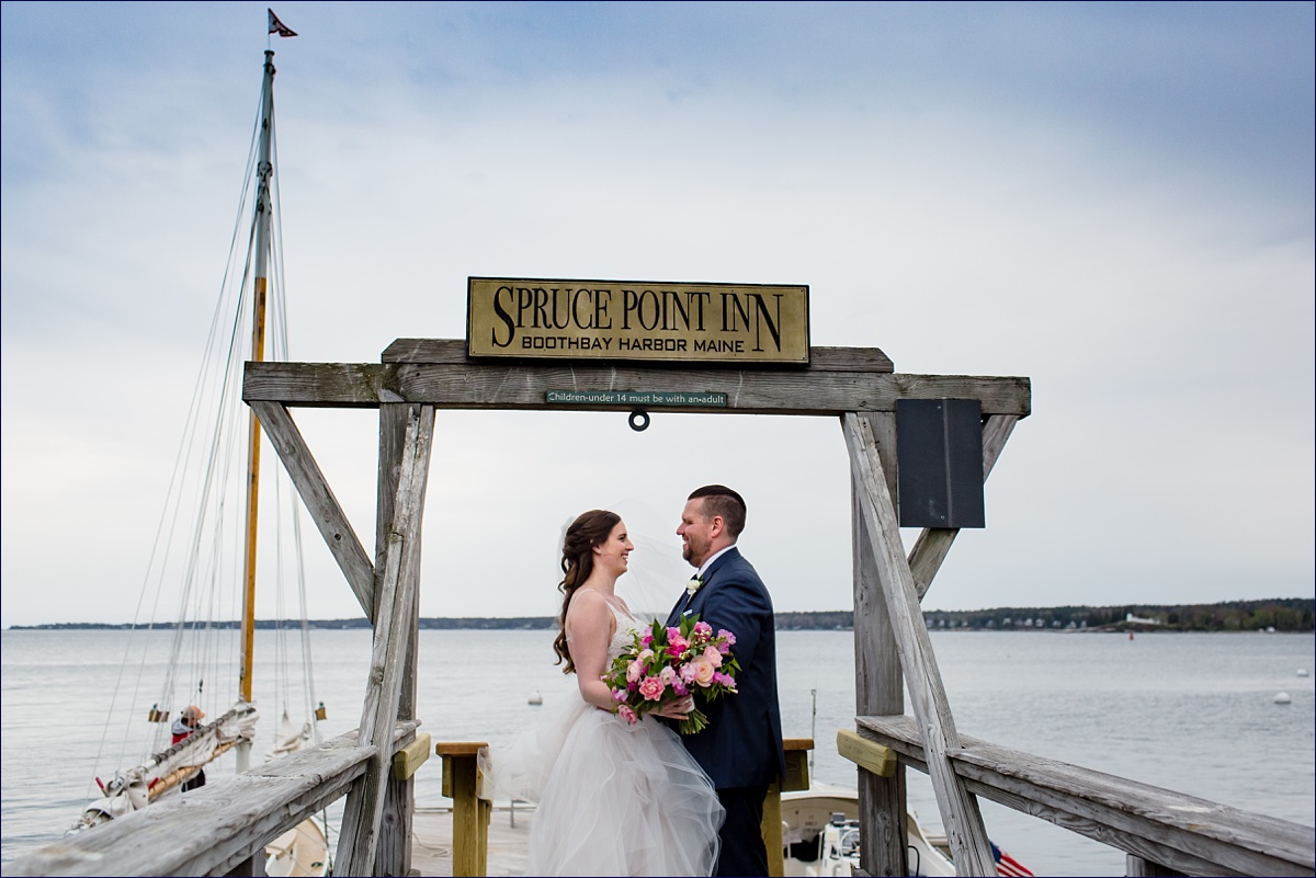 Spruce Point Inn Boothbay Harbor Maine Wedding the bride and groom hang out beneath the resort's sign against the backdrop of the ocean